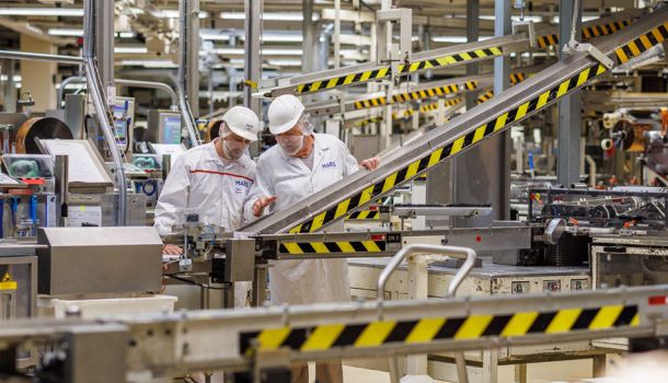 Zwei Mitarbeiter des Herstellers Mars stehen an einer Produktionsmaschine in einer Fabrik.
